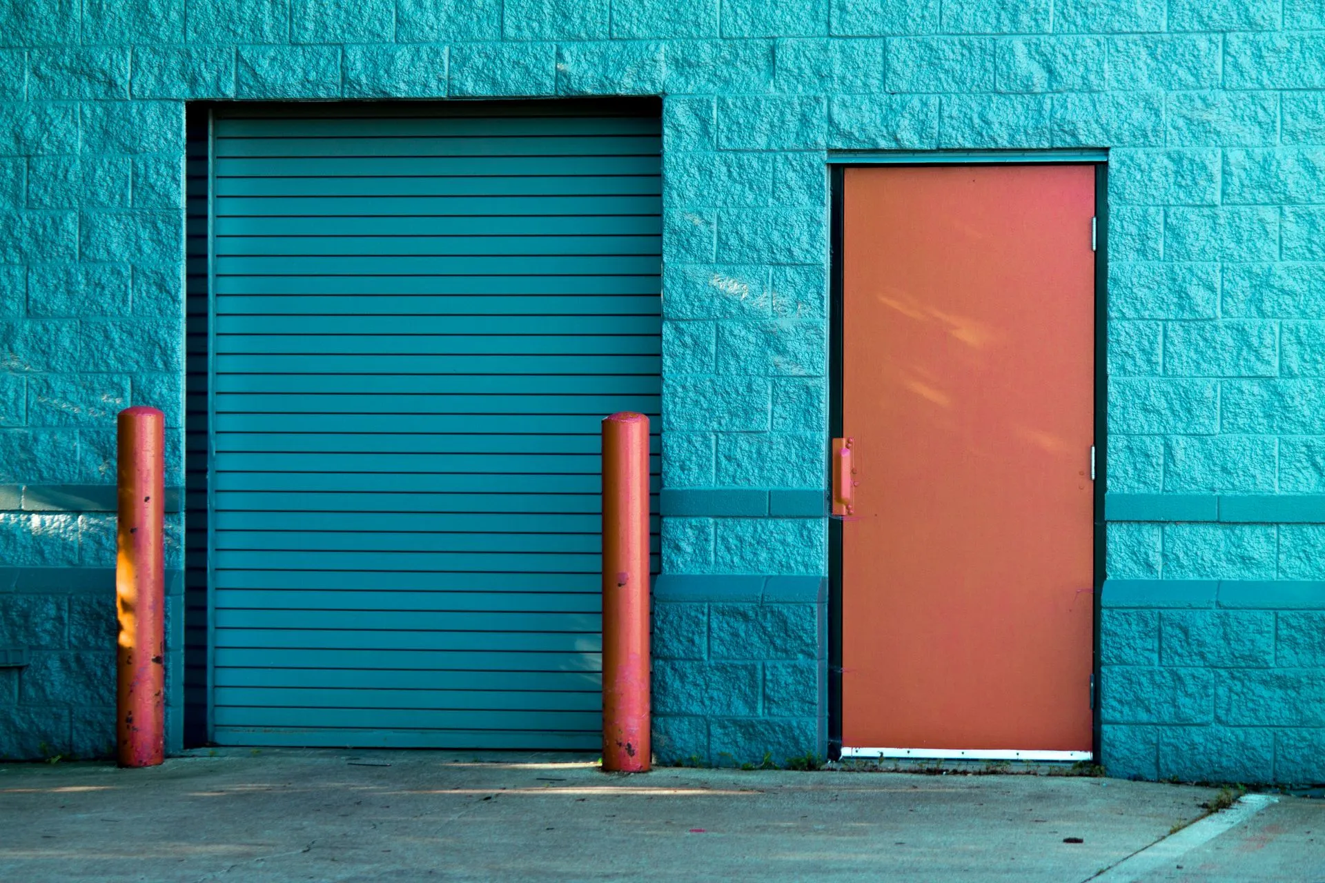Teal commercial roll-up door on a concrete block wall